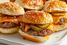 several hamburgers with cheese and pickles on a plate