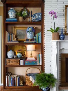 a bookshelf filled with lots of books next to a fireplace