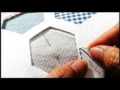 someone is cutting out some fabric on top of a piece of paper with scissors and thread