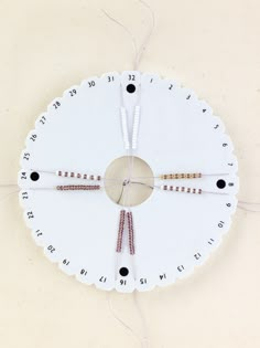 a clock that is hanging on the side of a wall with strings attached to it