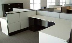 an empty office cubicle with black and white desks, cabinets and file cabinets