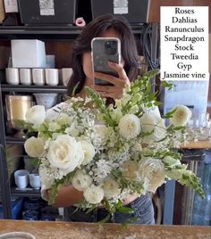 a woman taking a selfie while holding a bouquet of white flowers in front of her face