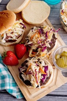 hamburgers with coleslaw and pickles on a cutting board