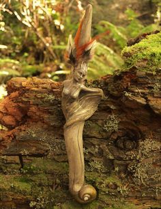 a statue is sitting on a log in the woods