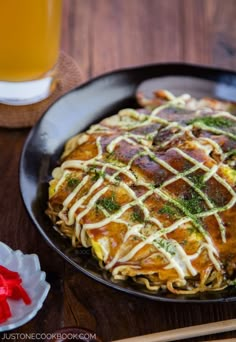 a pan filled with food sitting on top of a table next to a glass of beer