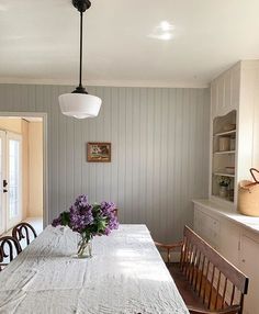 a dining room table with flowers in a vase on it