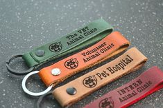 three leather keychains with the words volunteer animal clinic on them