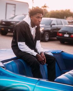 a man sitting on top of a blue car