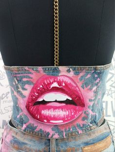 a woman's torso with pink lipstick painted on it and gold chains hanging from the waist