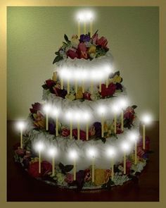 a three tiered cake decorated with flowers and candles