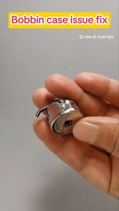 a person holding a small metal object in their left hand with the caption bobbin case issue fix