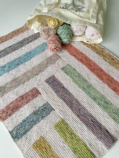 a crocheted rug with yarn and balls of yarn next to it on a white surface