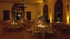 a banquet hall with tables and chairs set up for an event at night, lit by candles