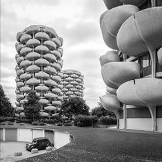 a black and white photo of a car parked in front of a tall building with lots of windows