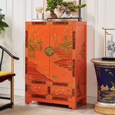 an orange cabinet sitting next to a chair and potted plant