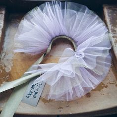 a white tulle wreath sitting on top of a piece of wood next to a pair of scissors