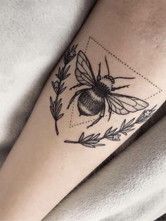 a black and white photo of a bee tattoo on the right arm with leaves around it