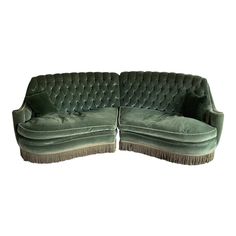 two green velvet couches with tassels on the ends and one facing each other