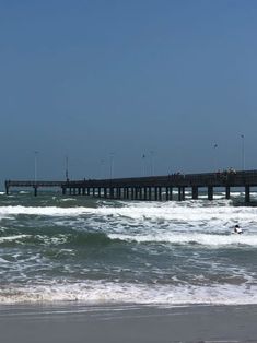 people are swimming in the ocean near a pier