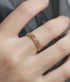 a close up of a person's hand wearing a gold ring with flowers on it