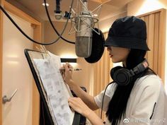 a woman writing on a piece of paper in front of a microphone with headphones