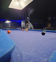 a man is playing pool in an indoor game room with balls on the floor and two people watching