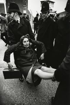 a woman sitting on the ground with her legs crossed and other people standing behind her