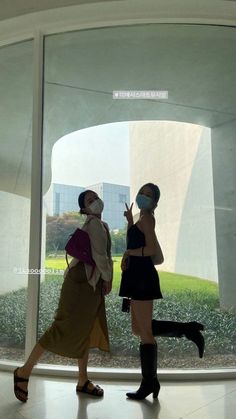 two women walking in front of a glass wall