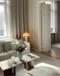 a living room filled with furniture and a white table in front of a large window