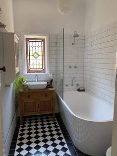 a bathroom with black and white checkered flooring next to a bathtub in the corner