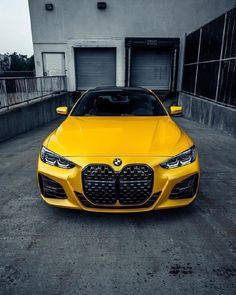 a yellow sports car parked in front of a building with two garage doors on each side