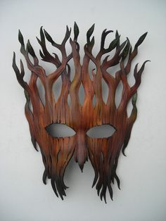 a mask made out of wood with leaves on it