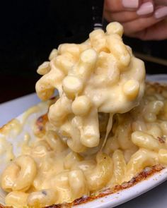 a white plate topped with macaroni and cheese on top of sauce covered bread