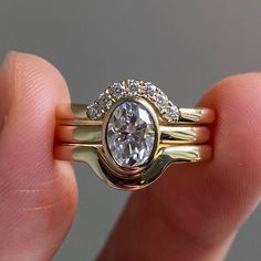 a close up of a person holding a gold ring with a diamond on the side