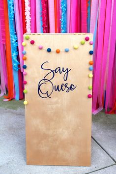 a sign that says say guess on it in front of colorful streamers and streamers