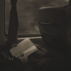 a person sitting on a train reading a book and looking out the window at something