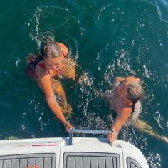 two people in the water on a boat with one person standing next to the other