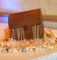 a wooden box sitting on top of a bed covered in seashells and pearls