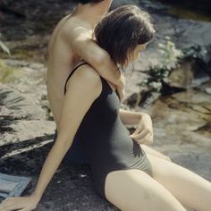 a man sitting next to a woman on top of a rock