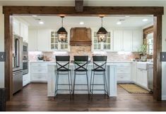 an open kitchen with white cabinets and black bar stools