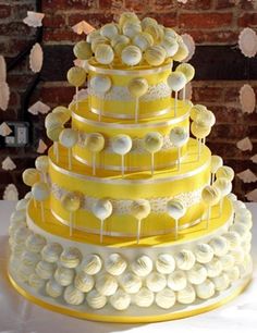 a yellow and white wedding cake with lots of candies on it's sides