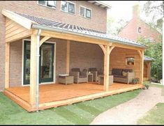 a covered patio with chairs and tables in front of a brick building on the grass