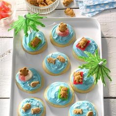 there are many cookies with blue frosting and teddy bears on them in the shape of boats