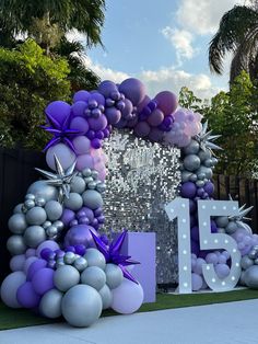 the balloon arch is decorated with purple and silver balloons