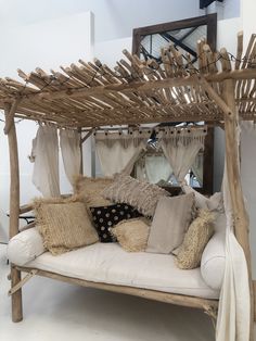 a white couch with pillows on it in front of a wooden bed frame and mirror