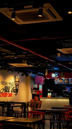 the inside of a restaurant with tables, chairs and neon signs on the wall above them