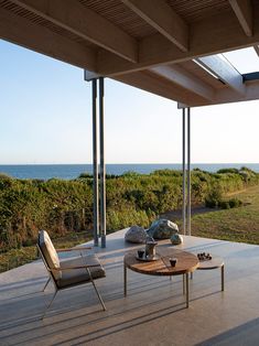 an outdoor living area with two chairs and a coffee table on the patio overlooking the ocean