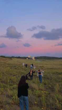 several people in a field flying kites at sunset