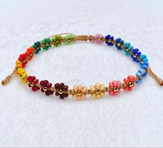 the multicolored beaded bracelet is on top of a white cloth covered surface