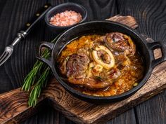 some food is in a black pan on a wooden board